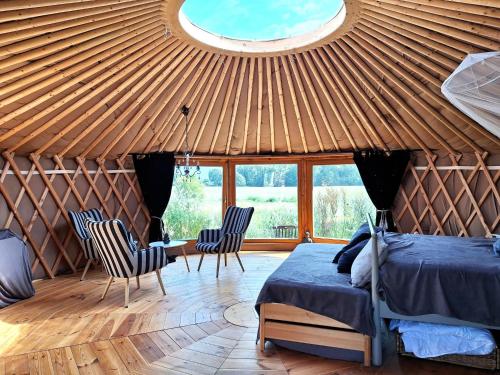 a room with a bed and chairs in a yurt at Glamour-Camping in Hanshagen