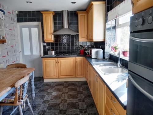 a kitchen with wooden cabinets and a sink at Semi Rural 3 Bed, loads of space in Pontypridd
