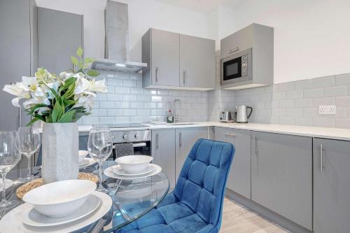 a kitchen with a glass table and blue chairs at Luxurious 2 Bedroom Apartment in Coulsdon