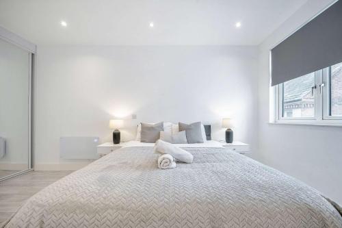 a white bedroom with a large bed with two lamps at Luxurious 2 Bedroom Apartment in Coulsdon