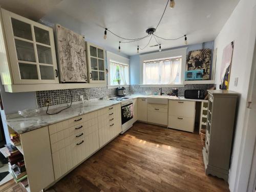 a kitchen with white cabinets and a wooden floor at Lakeview Suite by Trout Lake in Vancouver
