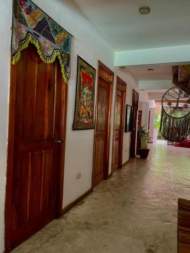 a hallway with wooden doors and paintings on the wall at Ganesh Hostel in El Valle