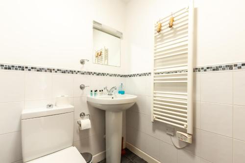 a white bathroom with a sink and a mirror at KGV Stays - Ocean View City Center Apartment in Southampton