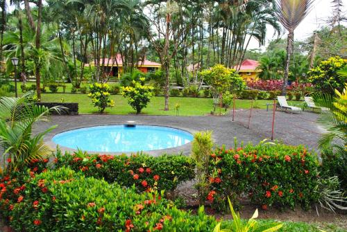 a swimming pool in a garden with flowers and plants at Hotel Arenal Country Inn in Fortuna