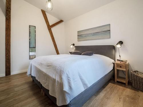 a bedroom with a large white bed and a wooden floor at West barn at Mühlendamm in Steinbergkirche