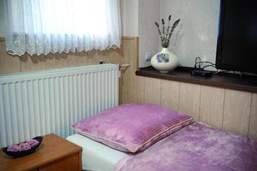 a bed with a purple pillow and a vase on a window at Lawendowe Studio in Starogard Gdański
