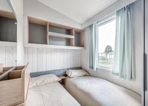 a small room with two beds and a window at Kippford View Holiday Park in Castle Douglas