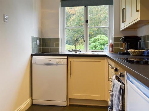 a kitchen with a sink and a dishwasher and a window at The Burrow in Haverthwaite
