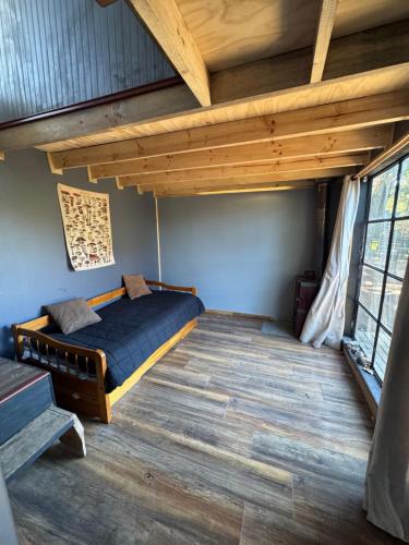a bedroom with a bed in a room with wooden ceilings at Cabaña con terraza vista al río in Melipeuco
