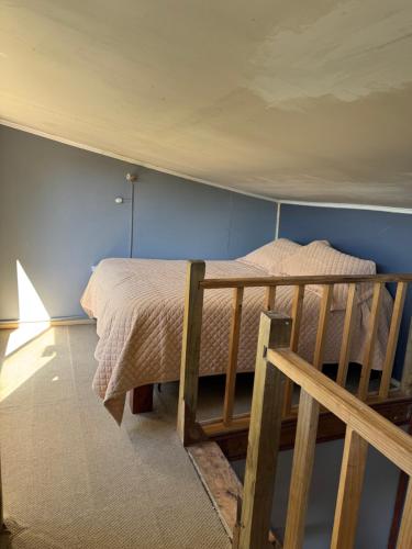 a bedroom with a bed and a wooden ladder at Cabaña con terraza vista al río in Melipeuco