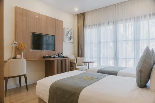 a hotel room with two beds and a flat screen tv at Villa Oasis in Luang Prabang