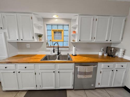 a kitchen with white cabinets and a sink and a window at Family & Pet-Friendly Home with Fenced Yard & Office in Munhall
