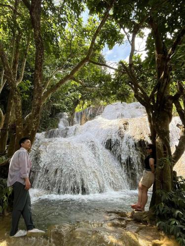 two people standing in front of a waterfall at Homestay Huong Hue Pu Luong in Làng Chiêu