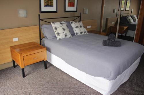 a bedroom with a large bed and a wooden table at Nautilus Beach Apartment 109 in Coffs Harbour