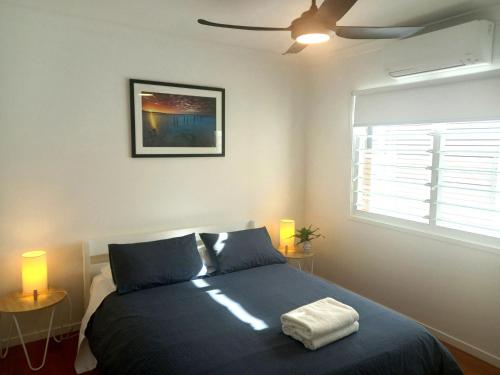 a bedroom with a bed with two lamps and a window at Sandy Feet - Rainbow Shores in Rainbow Beach