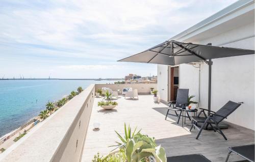 eine Terrasse mit einem Sonnenschirm, Stühlen und Meerblick in der Unterkunft Amazing Apartment In Pozzallo With Wifi in Pozzallo