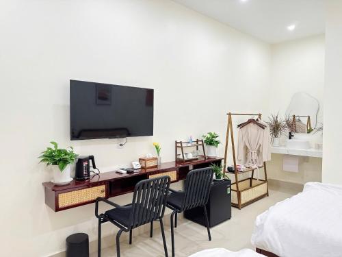 a bedroom with a desk with two chairs and a television on a wall at Malis Homestay in Trà Vinh