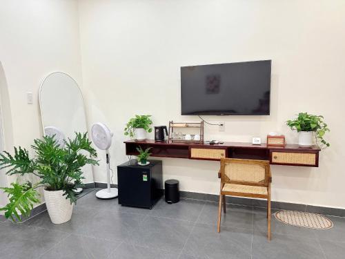 a room with a desk with a tv and plants at Malis Homestay in Trà Vinh