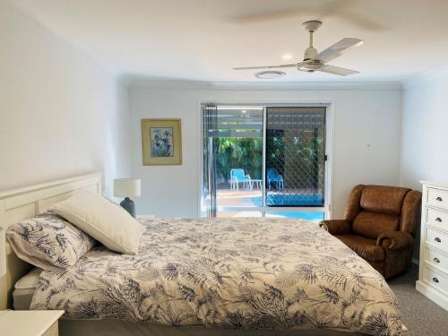 レインボー・ビーチにある29 Satinwood Drive - Rainbow Shores. Pets. Pool. Wifiのベッドと椅子のある寝室