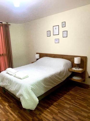 sypialnia z łóżkiem i dwoma obrazami na ścianie w obiekcie Serenity Apartment w mieście Cochabamba