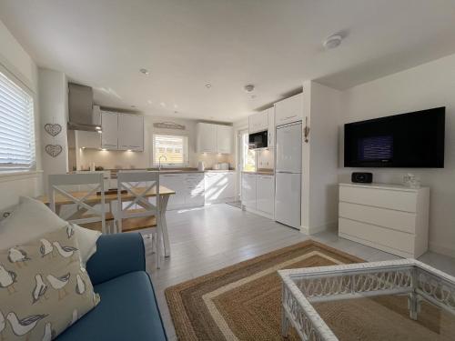 un salon avec un canapé bleu et une cuisine dans l'établissement Well Cottages, à Portmahomack