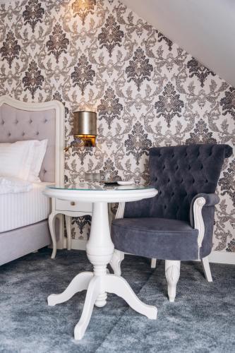 a bedroom with a table and a chair and a bed at Strindberg Boutique Hotel in Topliţa