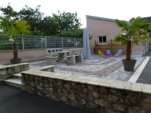 a patio with a table and chairs and palm trees at Gîte LAU'LIVIER- Piscine chauffée et couverte in Givarlais