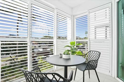 Una mesa y sillas en una habitación con ventanas. en Reefside at 201 Lake Street, en Cairns