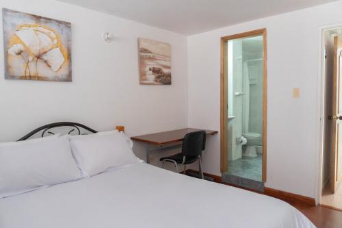 a bedroom with a bed and a desk and a bathroom at 100 Wonderful House in Bogotá
