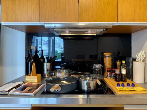 a kitchen counter with pots and pans on a stove at Expansive Luxury 2BR - Ultra Fast Wifi - Phrom Phong in Bang Kapi