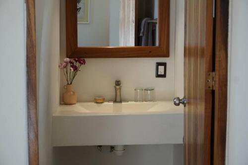 a bathroom sink with a mirror and a vase of flowers at Nicho Suite @ Sayulita Surfside Suites in Sayulita