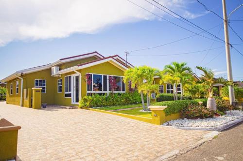 una casa amarilla con palmeras delante en Adorable Beach House in Draxhall Gated Pool Gym, en Steer Town