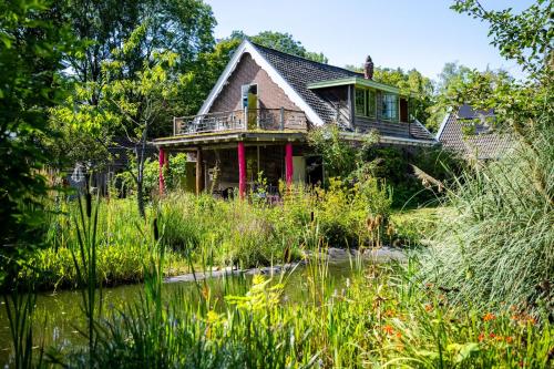 a house with a pond in front of it at Reijgershof - Yurt Experience with garden view in Amsterdam