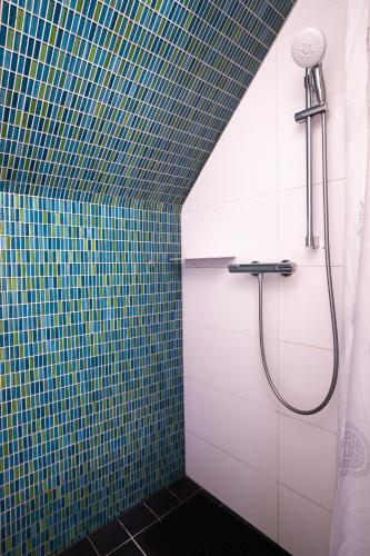 a shower in a bathroom with blue and green tiles at Reijgershof - Bali Suite with private terrace in Amsterdam