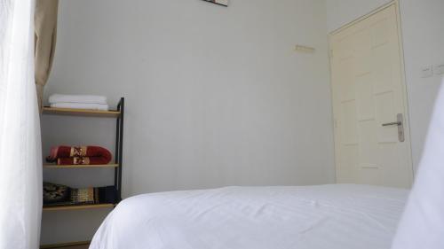 a bedroom with a white bed and a door at Diyar Villas Puncak M6/12 in Puncak