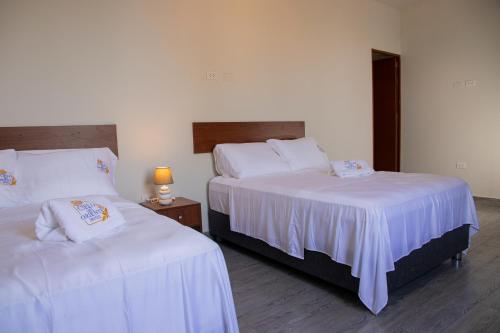 a bedroom with two beds with white sheets at Cielo del Oriente Hotel in Pucallpa