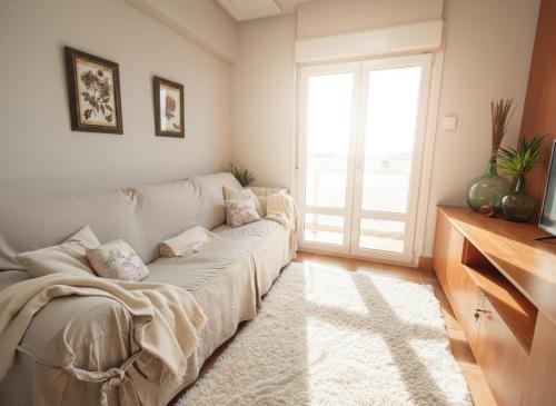 a living room with a white couch and a window at COSTA VASCA LEIOA - HoME in Leioa
