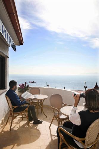 a man and woman sitting on a patio looking at the ocean at Hotel Boutique Vista Velero in Viña del Mar