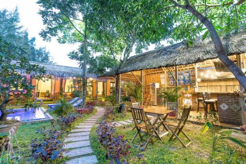 a house with a table and chairs in the yard at An Bang beach Happy Village in Hoi An