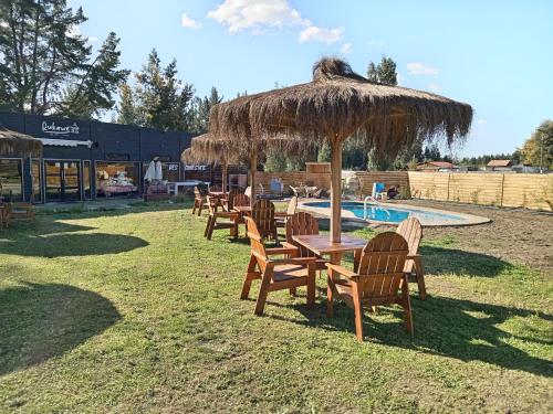 a group of tables and chairs under a straw umbrella at Rukawe Quillon in Quillón