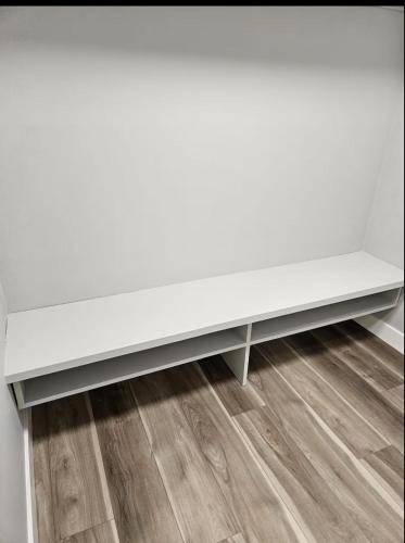 a white bench in a room with a wooden floor at Guest Home Near Regina Airport YQR in Regina