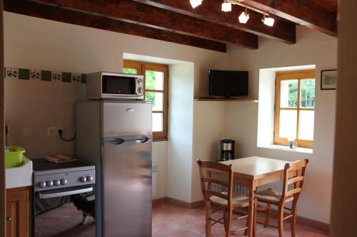 - une cuisine avec une table et un four micro-ondes au-dessus d'un réfrigérateur dans l'établissement Le Pigeonnier de Lacalm GÎTE, à Saint-Grégoire
