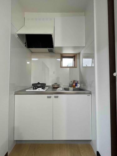 a small kitchen with white cabinets and a sink at Sweet house 东武练马201 in Tokyo