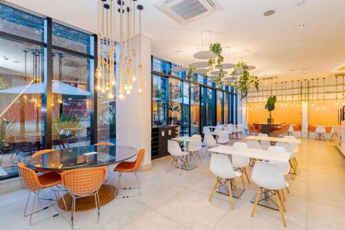 un ristorante con tavoli e sedie bianchi e finestre di Flat Região Nobre a Curitiba