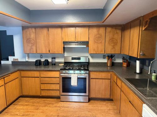 a kitchen with wooden cabinets and a stove top oven at Rustic Western Home Steps from Rte 66 & Grand Canyon Train Station in Williams