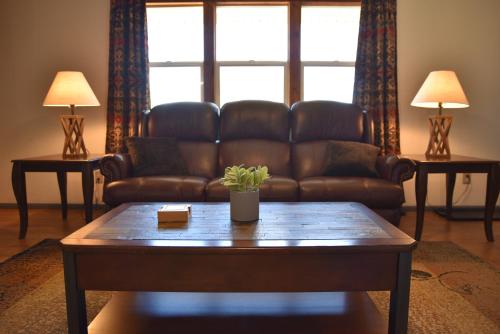 a living room with a leather couch and a coffee table at Rustic Western Home Steps from Rte 66 & Grand Canyon Train Station in Williams