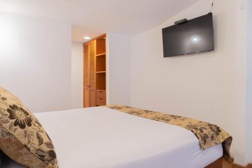 a bedroom with a bed with a television on the wall at 100 Wonderful House in Bogotá