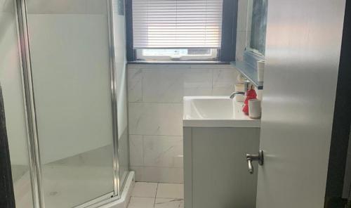 a white bathroom with a shower and a sink at Centrally Located Blue House in Halifax