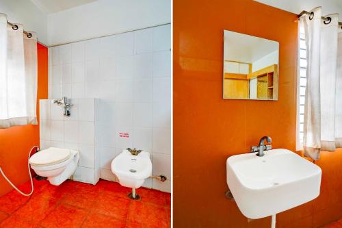 an orange bathroom with a toilet and a sink at Hotel O Rajkumar Road in Mysore