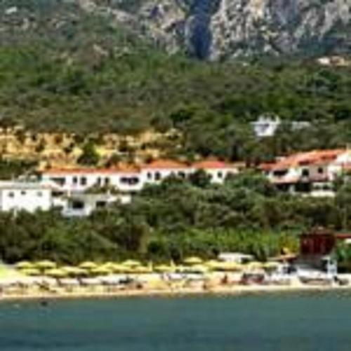 a group of houses on a hill next to the water at Limnionas Bay Village Hotel in Marathokampos